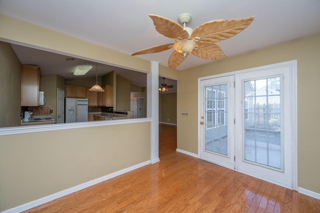 kitchen featuring white appliances, brown cabinetry, baseboards, ceiling fan, and light wood-type flooring