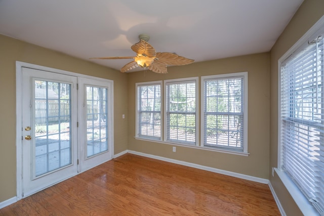 interior space with a ceiling fan, baseboards, and wood finished floors