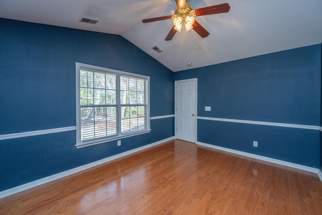 empty room with visible vents, baseboards, wood finished floors, and vaulted ceiling