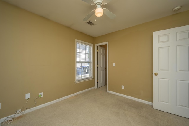 spare room with light carpet, visible vents, a ceiling fan, and baseboards