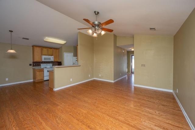 unfurnished living room with vaulted ceiling, a ceiling fan, visible vents, and light wood finished floors