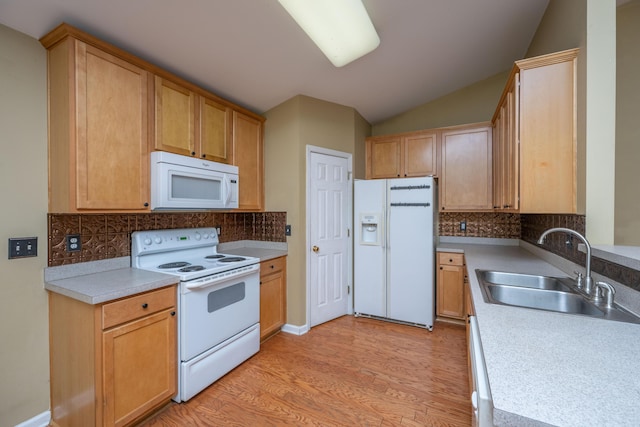 kitchen featuring light wood-style flooring, a sink, white appliances, light countertops, and vaulted ceiling