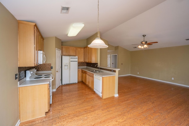 kitchen featuring light wood finished floors, vaulted ceiling, a peninsula, white appliances, and a sink