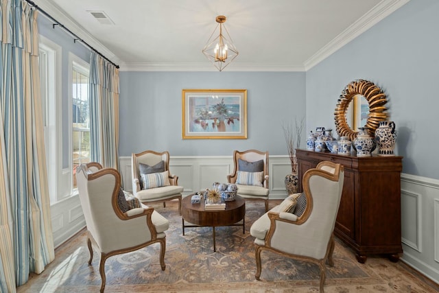 sitting room featuring ornamental molding, wainscoting, visible vents, and a decorative wall