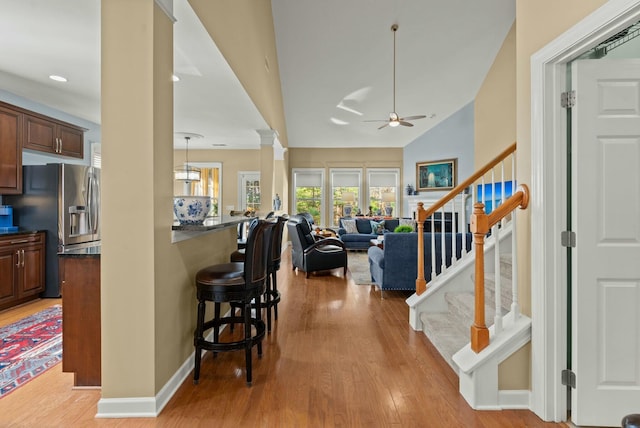 interior space with dark countertops, open floor plan, light wood-style floors, a kitchen bar, and stainless steel refrigerator with ice dispenser