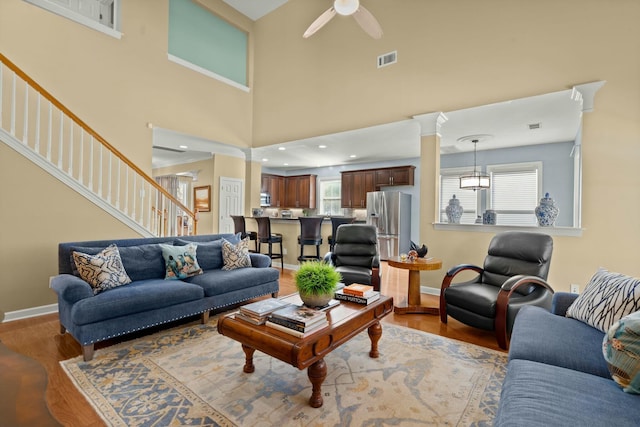 living room with baseboards, wood finished floors, a ceiling fan, and ornate columns