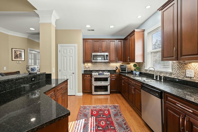 kitchen with stainless steel appliances, visible vents, light wood-style flooring, a sink, and ornate columns