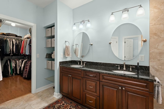 full bath with double vanity, tile patterned flooring, a sink, and a walk in closet