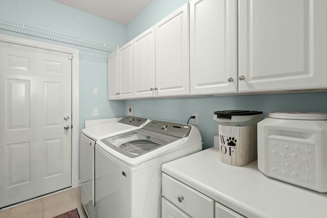 washroom with light tile patterned floors, washing machine and dryer, and cabinet space