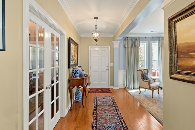 doorway to outside featuring decorative columns, baseboards, wood finished floors, crown molding, and french doors