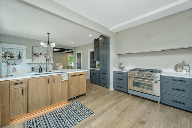 kitchen with light countertops, high end stainless steel range oven, light wood finished floors, and a notable chandelier