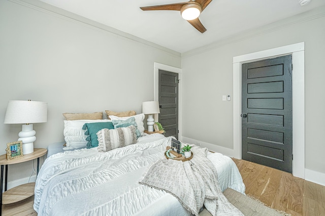 bedroom with crown molding, wood finished floors, ceiling fan, and baseboards