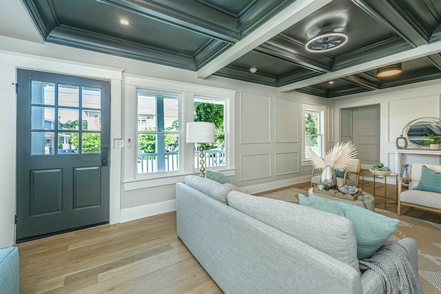 living room with light wood-type flooring, crown molding, coffered ceiling, and a healthy amount of sunlight