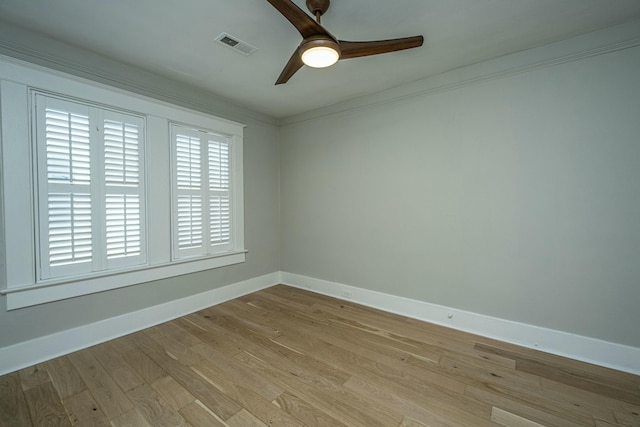 empty room with light wood-style flooring, ornamental molding, a ceiling fan, visible vents, and baseboards