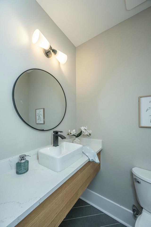 bathroom featuring tile patterned flooring, baseboards, a sink, and toilet