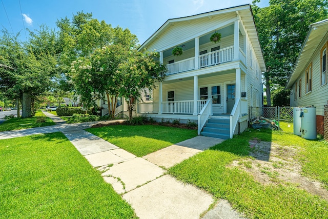 view of front of property with covered porch, a front yard, fence, a gate, and a balcony