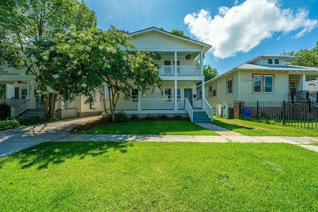 view of front facade featuring a porch, a balcony, fence, and a front lawn