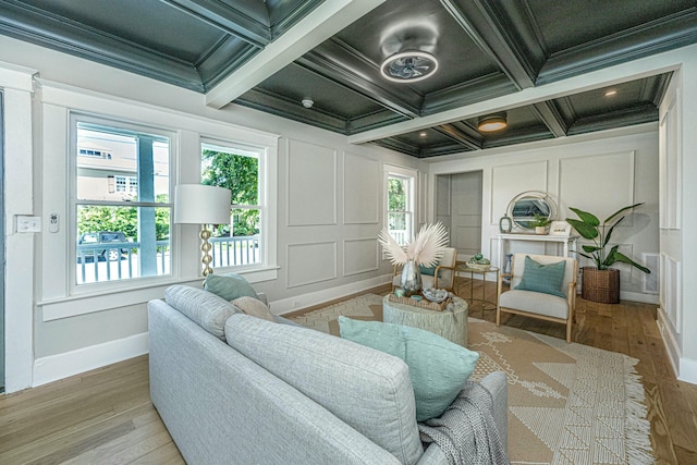 living area featuring crown molding, a decorative wall, and wood finished floors