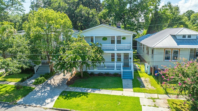 view of front of house with a balcony, stairway, a front yard, fence, and covered porch