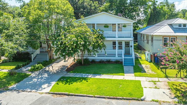 view of front of property featuring concrete driveway, a balcony, a front lawn, fence, and covered porch