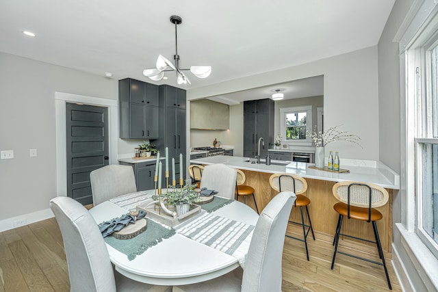 dining room with a chandelier, light wood finished floors, and baseboards