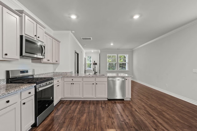 kitchen featuring dark wood-type flooring, stainless steel appliances, ornamental molding, kitchen peninsula, and light stone counters