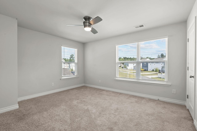 spare room with ceiling fan, light carpet, and a healthy amount of sunlight