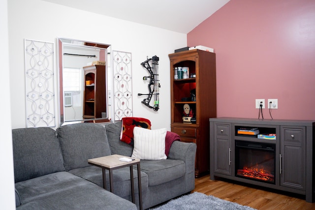 living area with a glass covered fireplace, cooling unit, and light wood finished floors