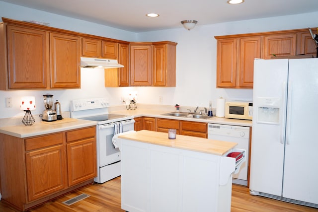 kitchen featuring light wood finished floors, white appliances, a sink, and under cabinet range hood