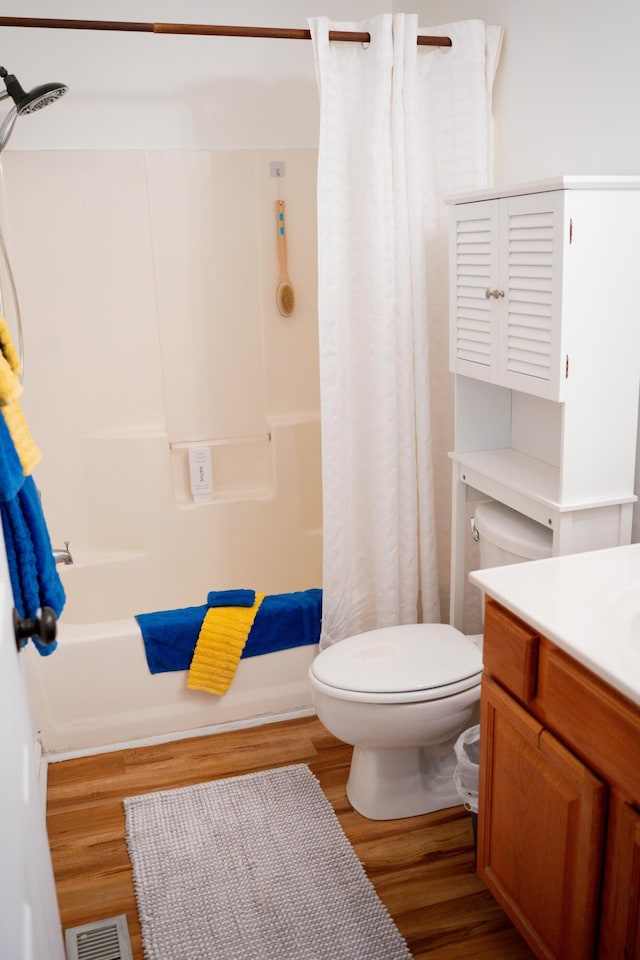 full bath with visible vents, toilet, shower / bath combo with shower curtain, vanity, and wood finished floors