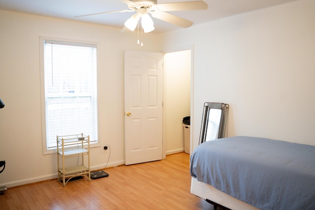 bedroom featuring light wood-style floors, multiple windows, ceiling fan, and baseboards