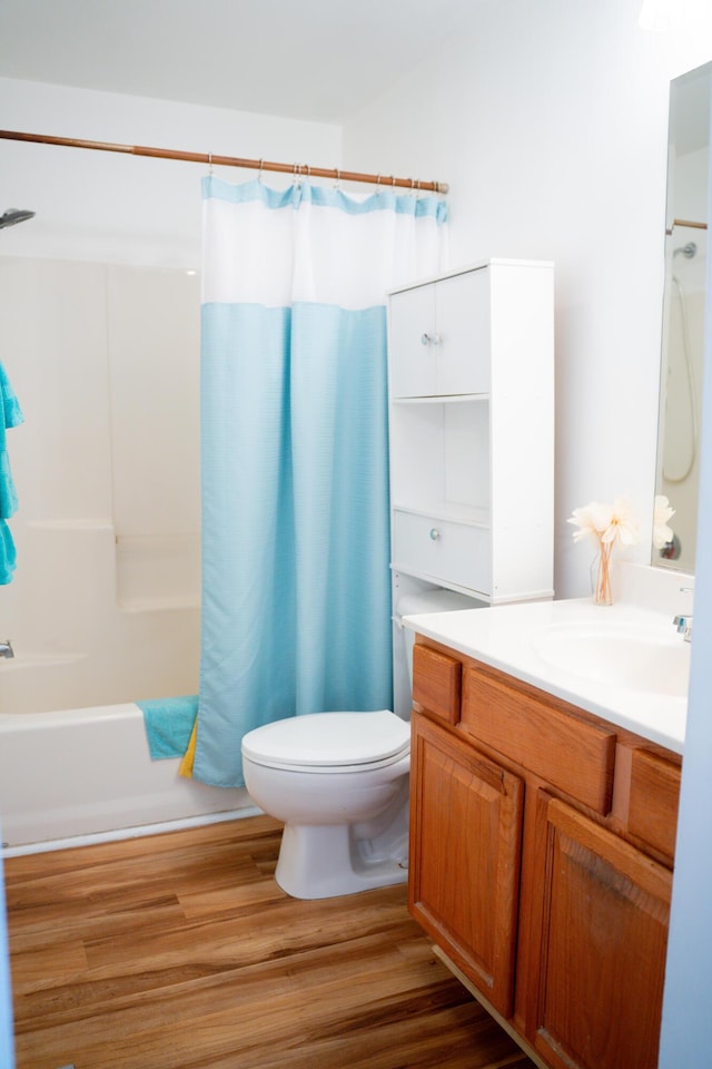 full bathroom with toilet, shower / bath combo with shower curtain, wood finished floors, and vanity