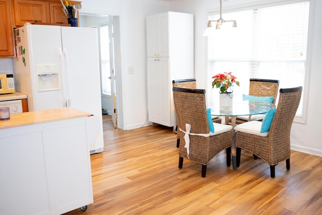 dining space with an inviting chandelier, light wood-style flooring, and baseboards