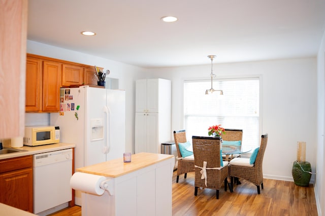 kitchen featuring pendant lighting, recessed lighting, light countertops, light wood-type flooring, and white appliances