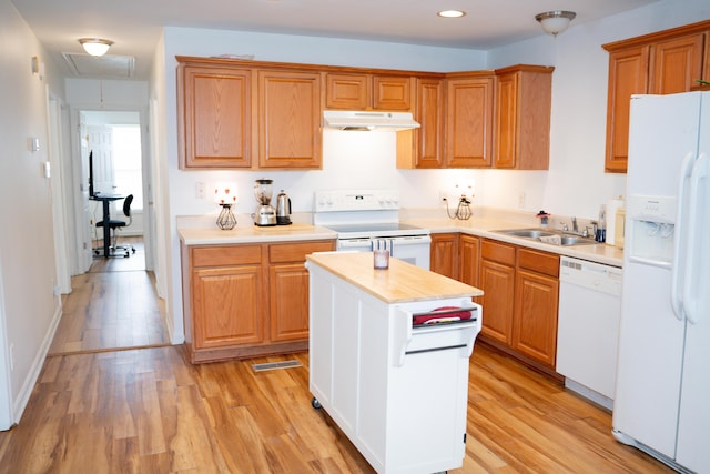 kitchen with white appliances, under cabinet range hood, light countertops, and a sink