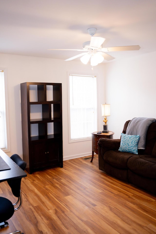 living room with light wood-style floors, a healthy amount of sunlight, and a ceiling fan