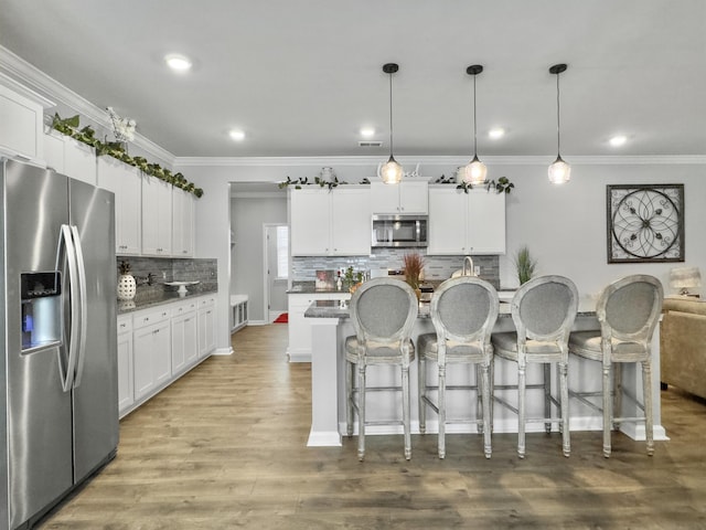 209 Celestial Blvd, Summerville, SC 29486 - kitchen featuring appliances with stainless steel finishes, crown molding, backsplash, white cabinetry, and a breakfast bar