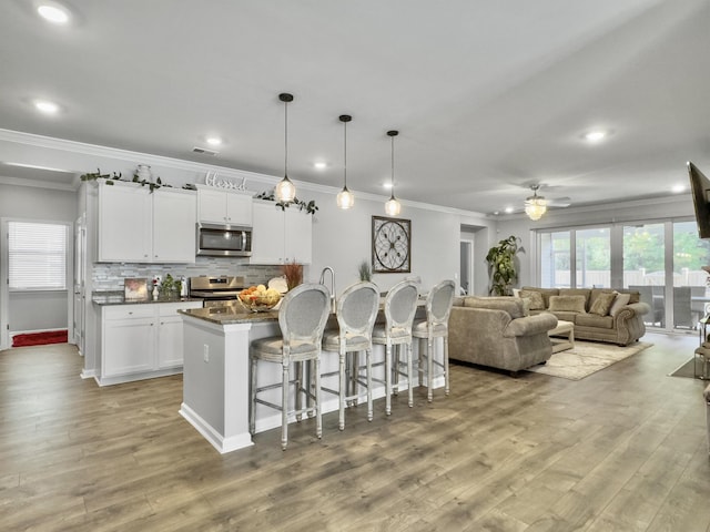209 Celestial Blvd, Summerville, SC 29486 - kitchen featuring appliances with stainless steel finishes, crown molding, a breakfast bar, ceiling fan, and light wood-style floors