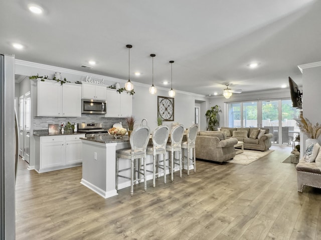 209 Celestial Blvd, Summerville, SC 29486 - kitchen featuring appliances with stainless steel finishes, ornamental molding, a kitchen bar, open floor plan, and light wood-style flooring