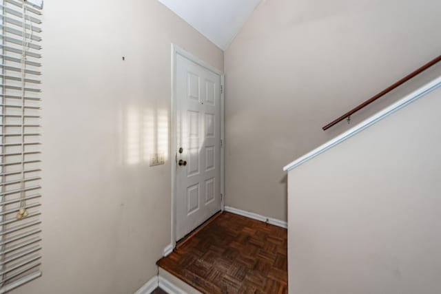 foyer featuring dark parquet flooring and lofted ceiling