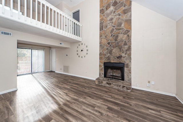 unfurnished living room with high vaulted ceiling, dark wood-type flooring, and a stone fireplace