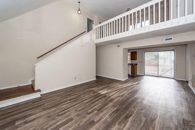 unfurnished living room featuring high vaulted ceiling and dark wood-type flooring