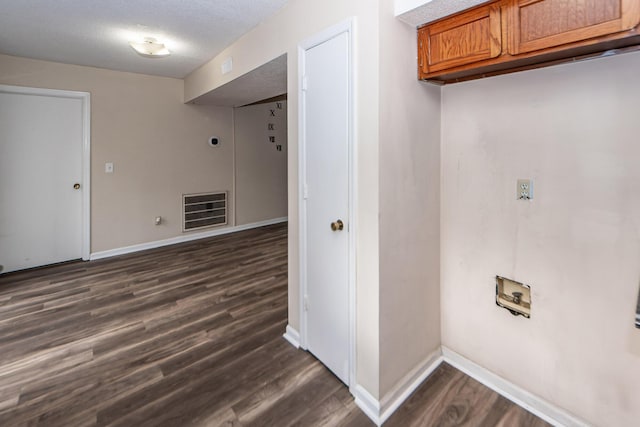 laundry area featuring cabinets, a textured ceiling, and dark wood-type flooring