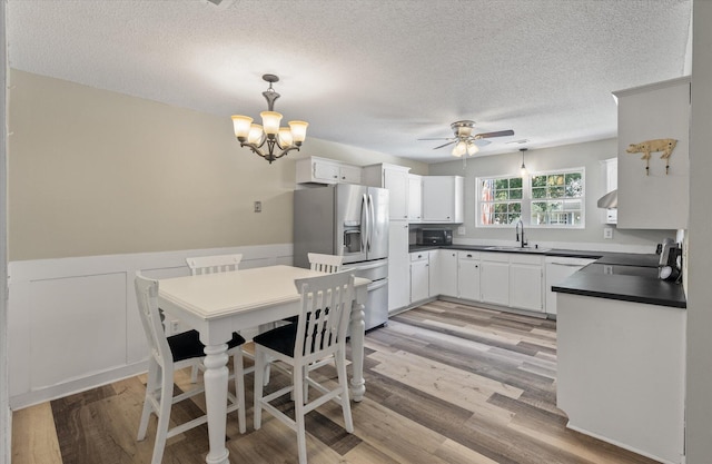 5052 Hidden Forest Ln, North Charleston, SC 29420 - dining space with a textured ceiling, a ceiling fan, light wood-style floors, a chandelier, and wainscoting