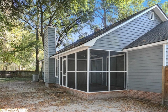 back of property with central AC and a sunroom