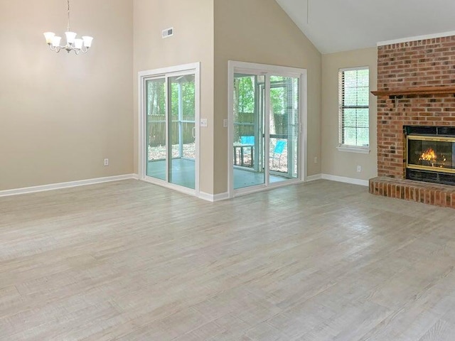 unfurnished living room featuring a fireplace, light hardwood / wood-style floors, high vaulted ceiling, and a chandelier