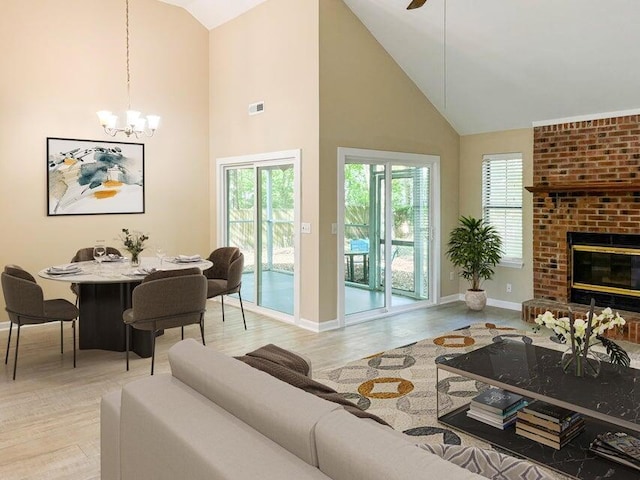 living room with a wealth of natural light, light wood-type flooring, a fireplace, and high vaulted ceiling