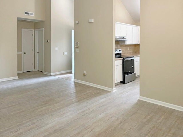 interior space with white cabinetry, stainless steel range with electric cooktop, light hardwood / wood-style floors, and high vaulted ceiling