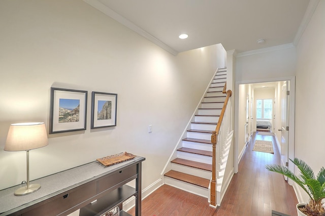 stairs featuring recessed lighting, wood finished floors, baseboards, and ornamental molding