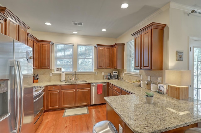 kitchen with visible vents, light wood-style flooring, a sink, appliances with stainless steel finishes, and a peninsula